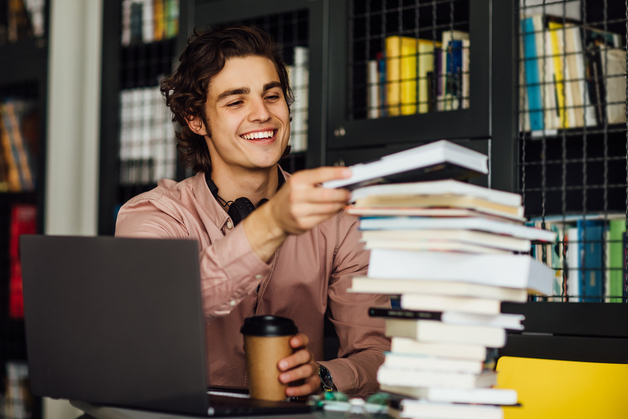 homem colocando um livro na pilha d elivros