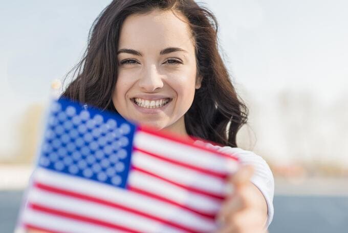 mulher sorrindo segurando bandeira dos estados unidos
