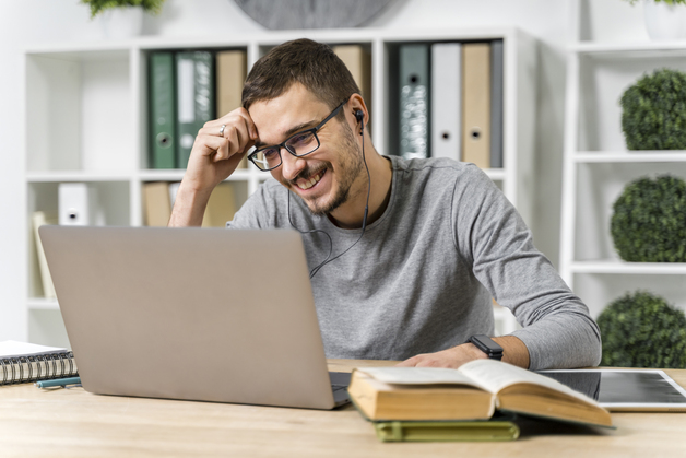 homem sorrindo pra tela do computador em biblioteca