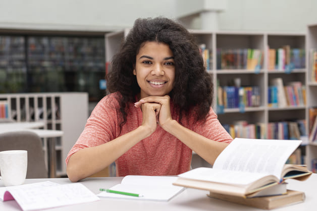 menina sorrindo na bibliotceca com camisa rosa